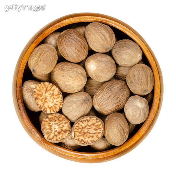 Whole and halved nutmegs, dried seeds, in a wooden bowl 이미지 (1283022070