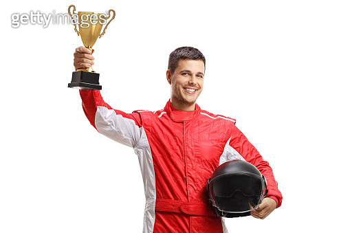 Young male car racer standing and holding a helmet and a gold trophy ...