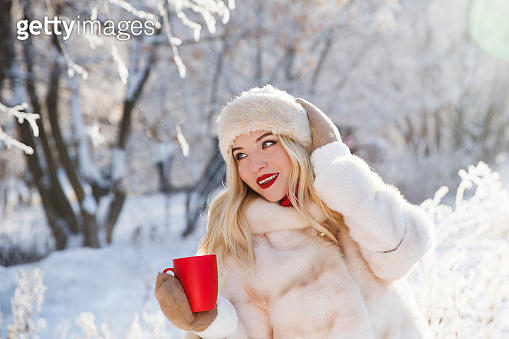 beautiful girl drinks hot tea or chocolate in the cold on a winter walk ...
