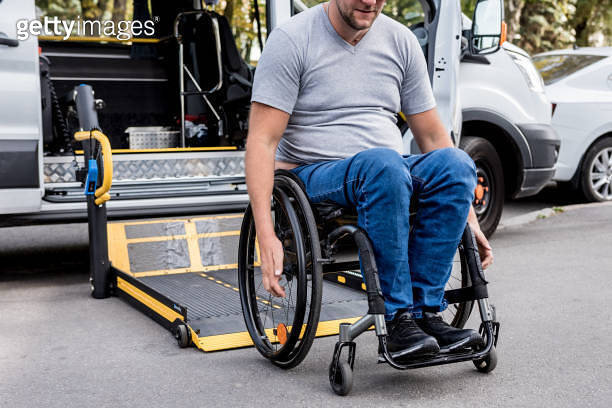 A man in a wheelchair on a lift of a vehicle for people with ...