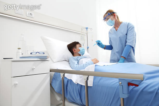 Nurses Fever nurse with thermometer measures fever on patient child in hospital bed ...