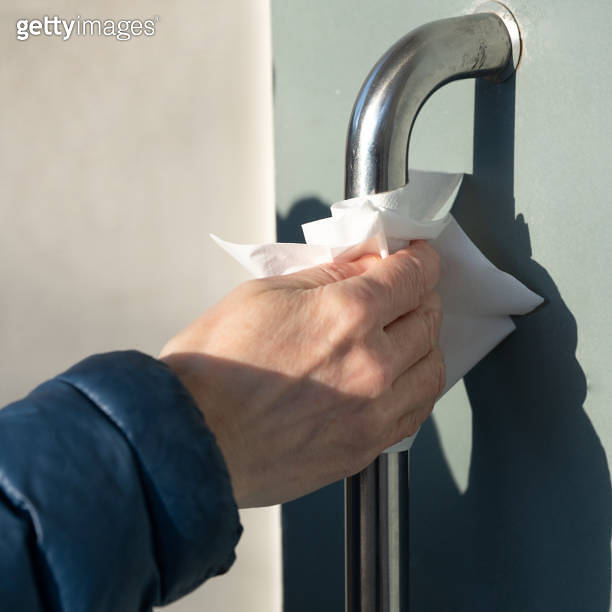 Woman uses a napkin when opens a porch door to protect from coronavirus