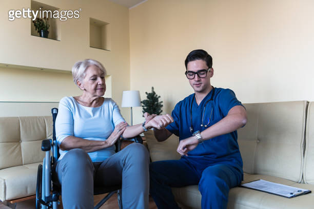 Young Doctor is Checking a Blood Pressure of a Disabled Senior Woman