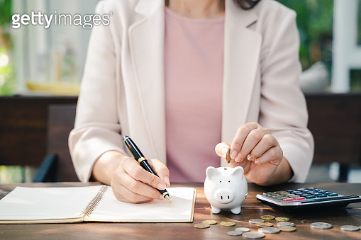 Closeup of business woman hand putting money coin into piggy bank for ...
