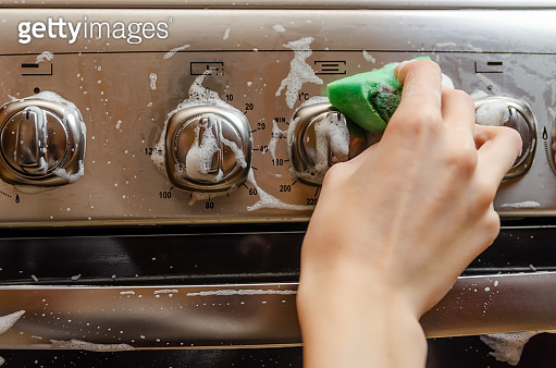 Switching Sponge woman's hand washes a green sponge with foam on the switch handle of a ...