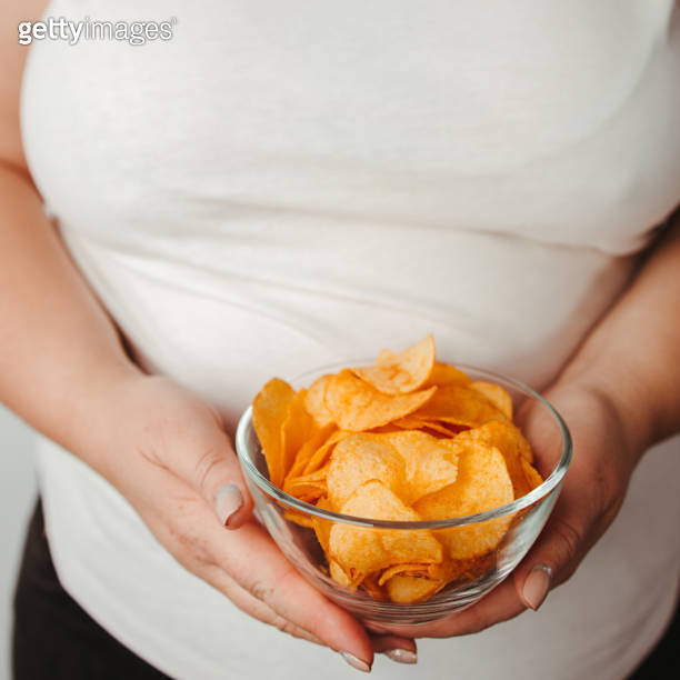 Overweight woman eating fattening potato chips 이미지 (1279868122) 게티이미지뱅크