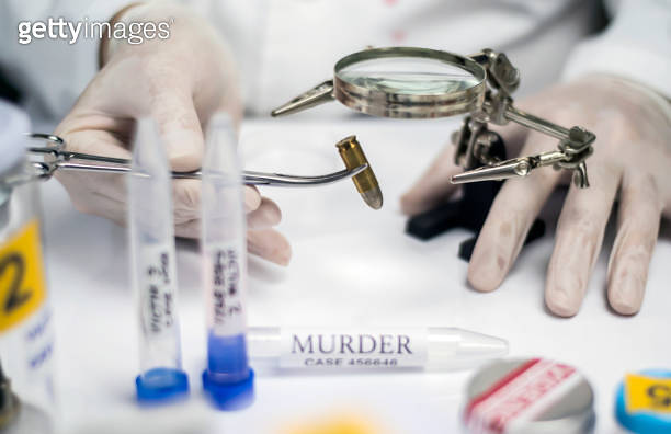 Expert police examines a bullet cap in scientific laboratory with ...