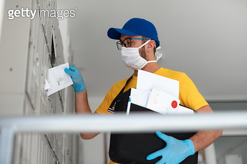 Mailman delivering mail with mail-bag and protective mask and gloves