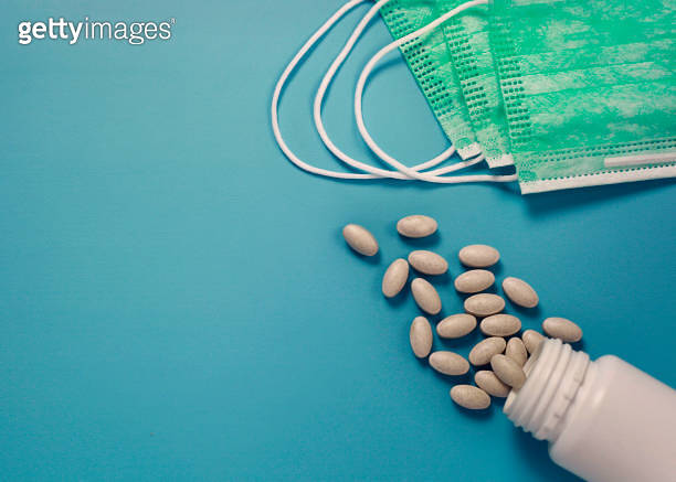 Medical face masks and Vitamin C tablets isolated on blue background ...