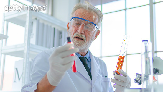 Senior professor male researcher tests a chemical liquid tube with face ...