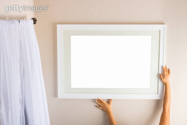 Hanging a blank white picture frame on a beige wall for decoration. 이미지 ...