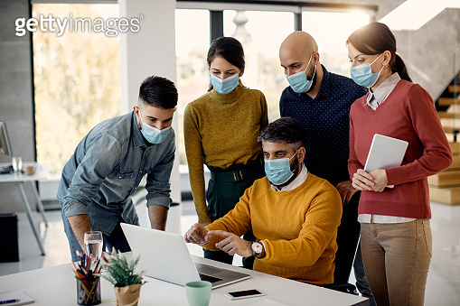 Business team wearing face masks while working on a computer in the ...