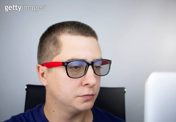 The programmer's glasses reflect lines of code. Programming ...