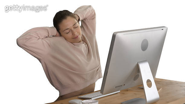 Relaxed Computer User Happy relaxed young woman sitting stretching in front of computer on ...