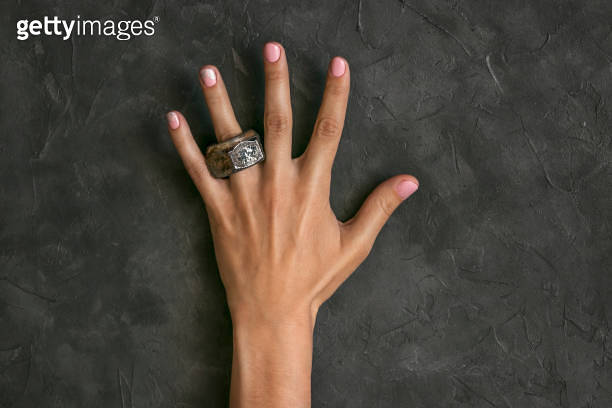 A rusty nut is placed on the finger of a beautiful female hand with a ...