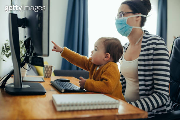 Young mother working with her baby on computer at her home office. 이미지 ...