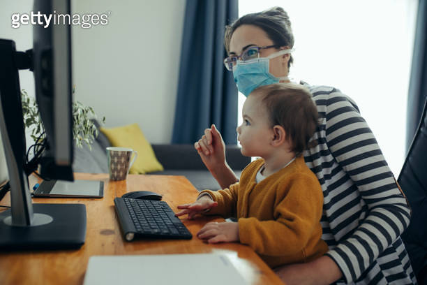 Young mother working with her baby on computer at her home office. 이미지 ...