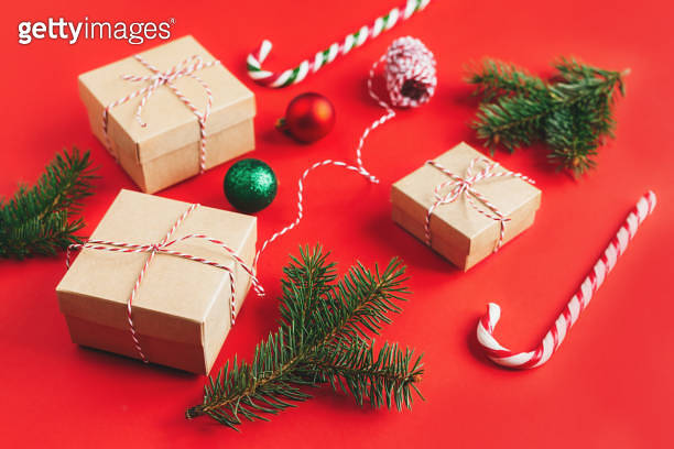 Craft gift boxes with spruce branches, balls and candy canes on a red ...