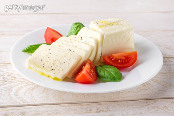 Rectangular slices of mozzarella cheese, fresh basil and quarters of ...