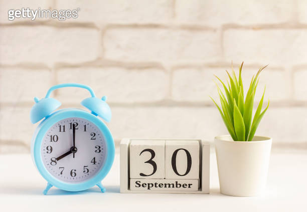 September 30 on a wooden calendar next to the alarm clock.September day ...