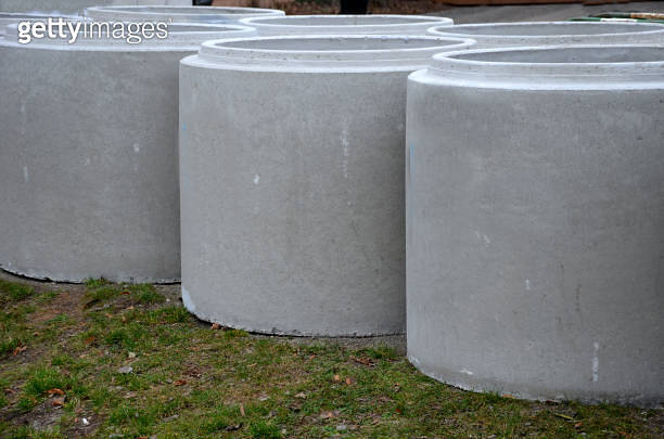 large concrete rings for the installation of sewers lined up on the ...