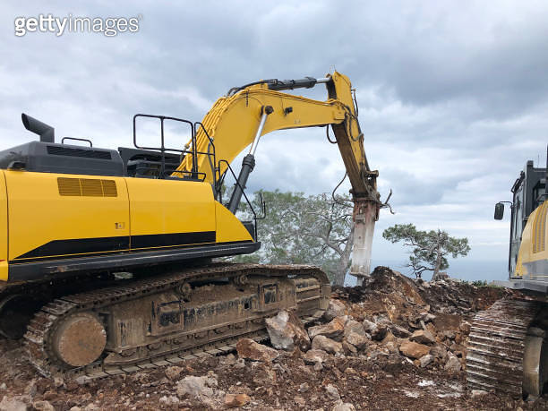 Hydrohammer Compactor Excavator and hydrohammer during road construction on the rocky soils ...
