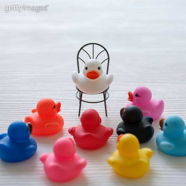 Group of multicolor rubber ducks, gathered around as if listening to a