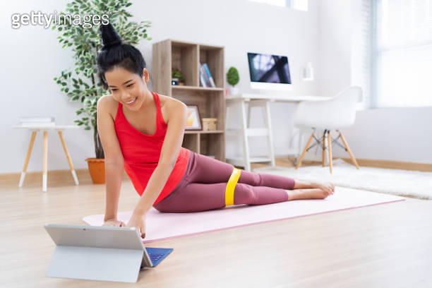 Asian Exercise Methods Asian woman See exercise methods from the tablet. She uses rubber ...