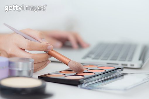Eye Makeup Computer Hands of woman with learning makeup with brush on cheek on laptop ...