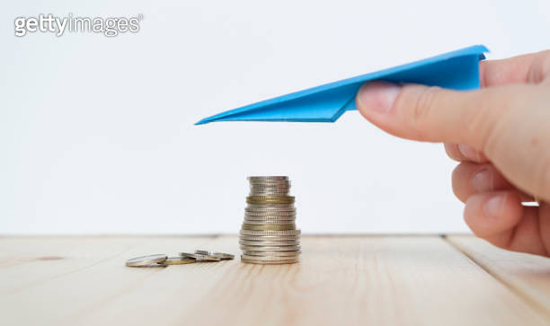 Paper Plane Coin Hand with a paper plane over a stack of coins. Income reduction concept ...