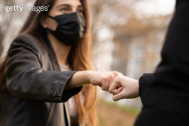 Two girls using fist bump as an alternative handshake outdoors in ...