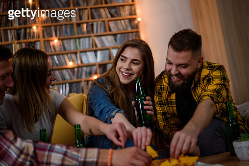 Friends hanging together on a house party drinking beer and eating ...