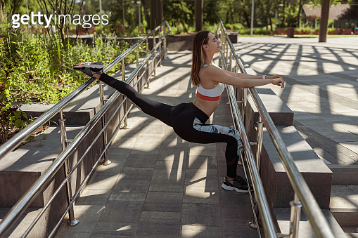 Lady Body Rear Side Ramp Design Beautiful lady does stretching exercise on ramp with metal railings in ...