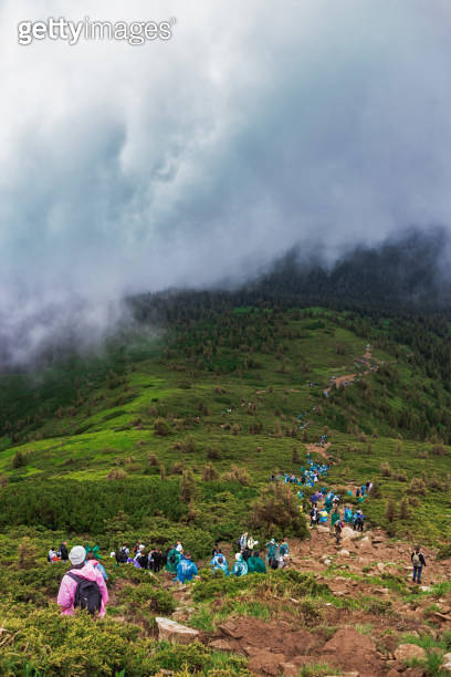 Tourist trail with a lot of tourists. Scenic view of mountains against ...