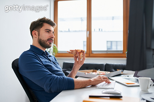 Young computer programmer eating pizza working from home (1347737300 ...