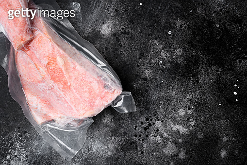 Snapper fish frozen pack meat, on black dark stone table background ...
