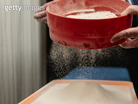 A man sows flour through a sieve. (1321162368) - 게티이미지뱅크