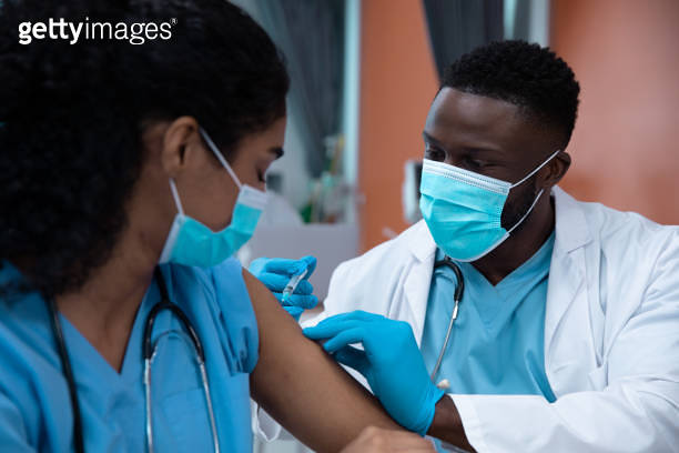 Mixtet Injection Mixed race couple of doctors wearing face masks making injection 이미지 ...