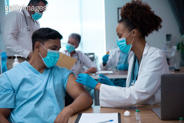 Mixtet Injection Mixed race couple of doctors wearing face masks making injection 이미지 ...