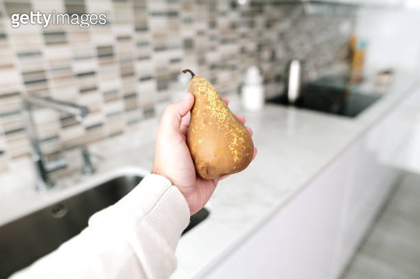 Hand holding a pear in a kitchen 이미지 (1350001916) - 게티이미지뱅크
