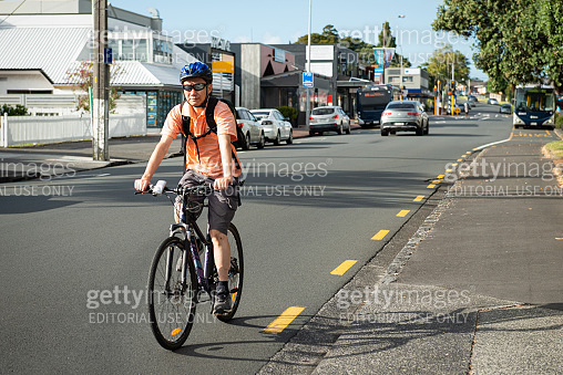 A cyclist riding to work on the road with out-of-focus cars and bus in ...