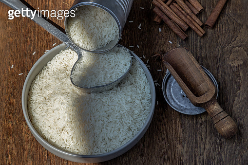 Thai jasmine rice pouring from old steel can with steel dipper on bowl ...
