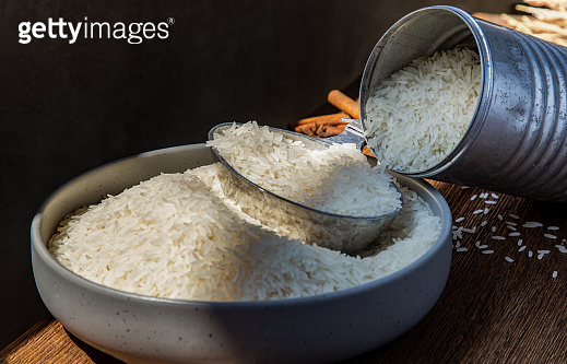 Thai jasmine rice pouring from old steel can with steel dipper on bowl ...