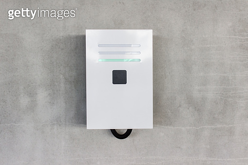 Electric charging station on concrete gray wall in underground parking ...