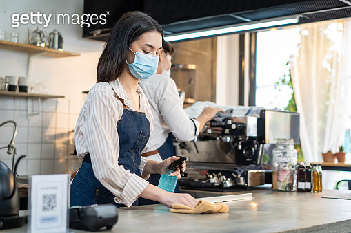 Cafe waiter wear mask, clean restaurant with sanitizer to open store ...