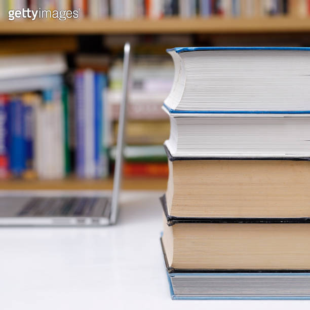 Stack of books and computer at the library 이미지 (1302322331) - 게티이미지뱅크