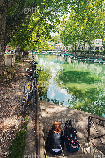 Two women resting in front of Annecy canal in springtime - Haute-Savoie ...