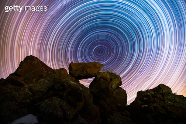 The rocks silhouette on the hill under the colorful star trails on the ...