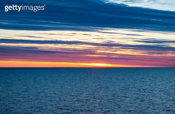 Bright orange sunset over the sea and sun on a blue sky and rows of ...