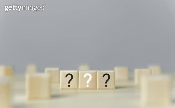 several wooden blocks Three question marks are displayed. On a gray ...
